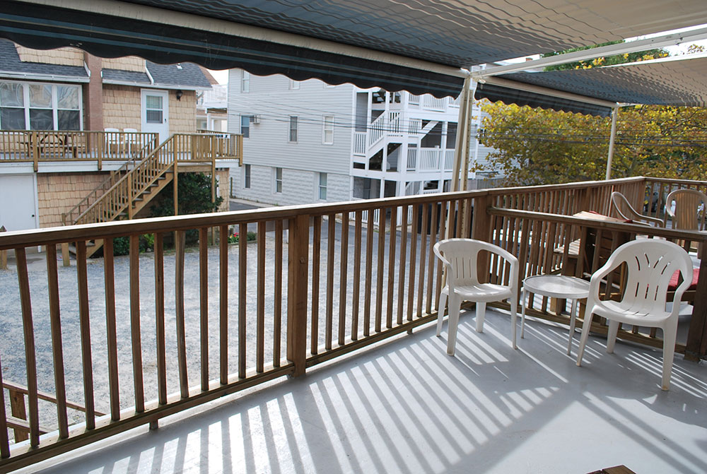 two white chairs sitting on top of a wooden balcony