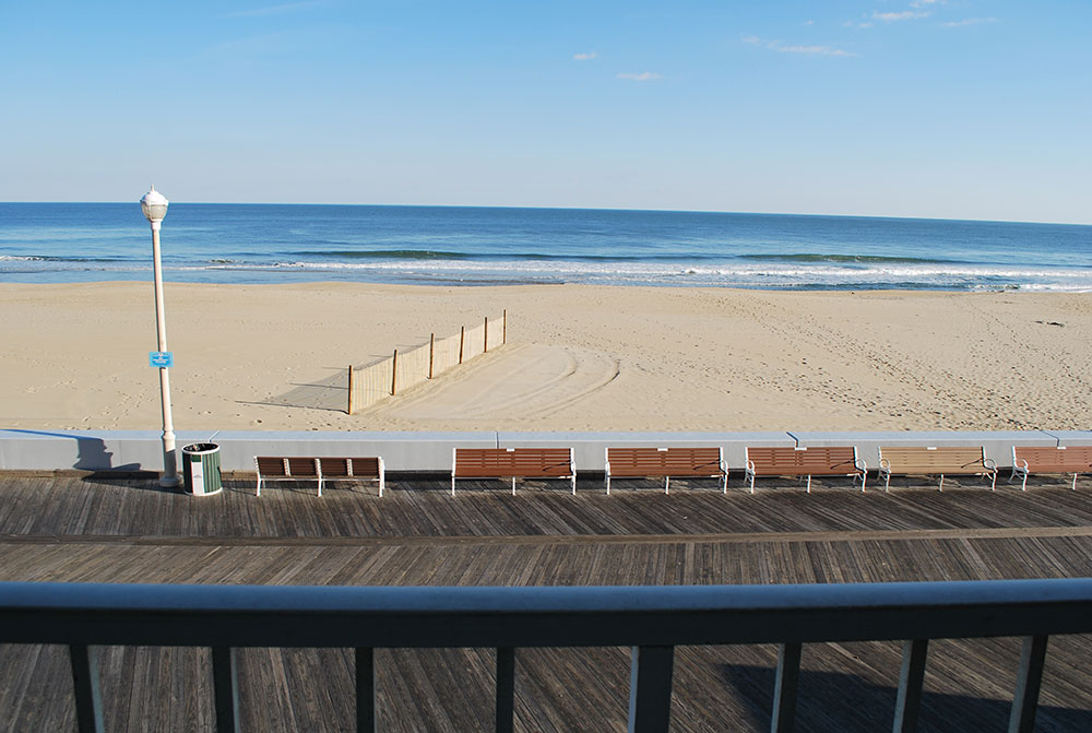a row of wooden benches sitting on top of a sandy beach