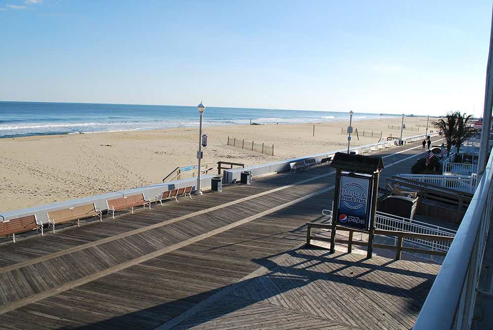 a boardwalk next to the ocean with benches on it