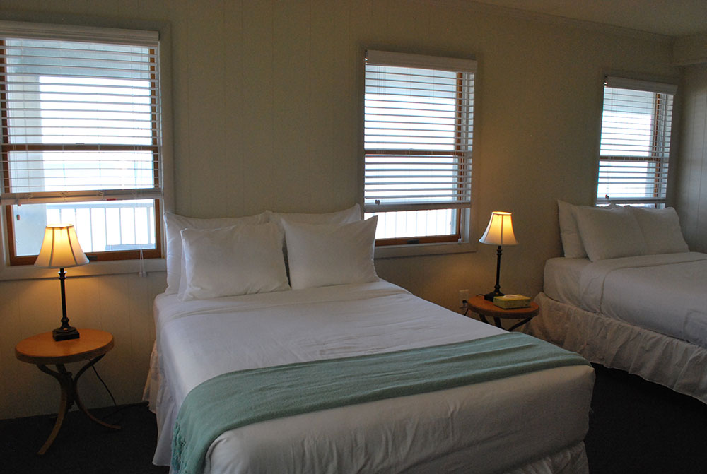 two beds in a room with three windows