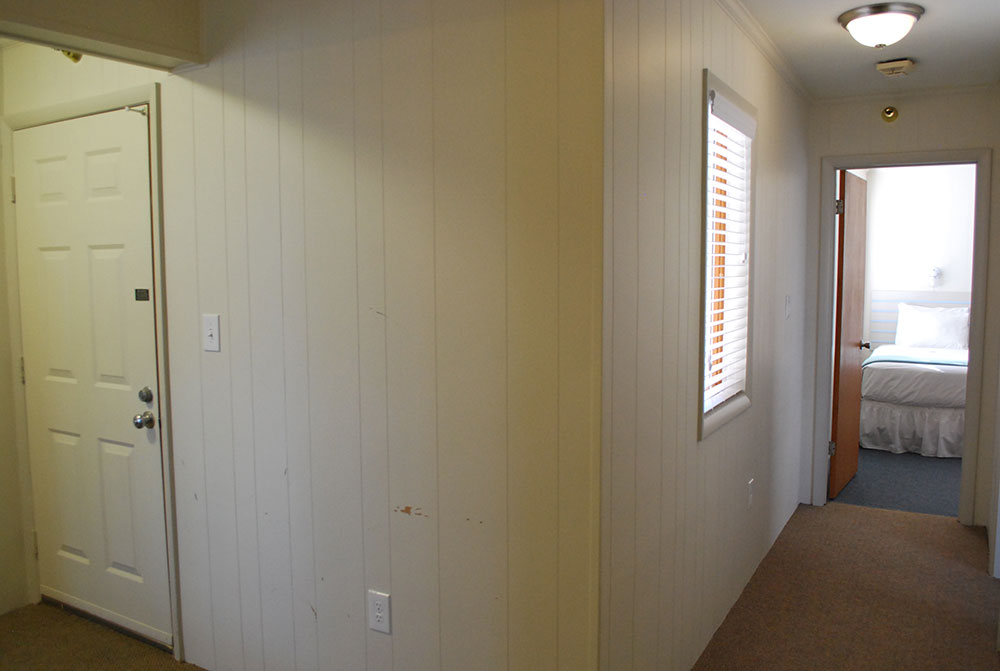 a hallway leading to a bedroom with white walls