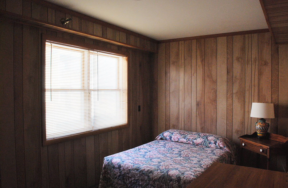 a bedroom with wood paneling and a bed