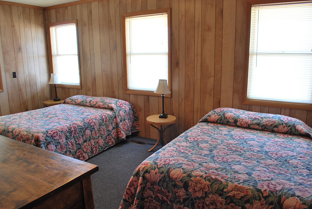 two beds in a room with wood paneling