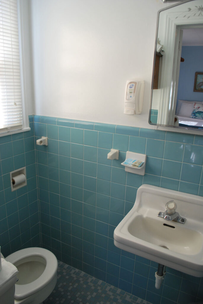 a blue tiled bathroom with a white toilet and sink