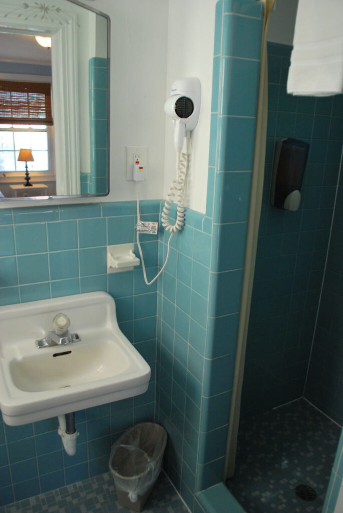 a blue tiled bathroom with a sink and shower