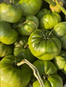 a pile of green tomatoes sitting on top of a table