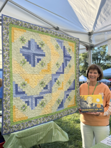 a woman holding a quilt in front of a tent