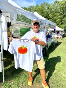 a man holding a t - shirt with a tomato on it