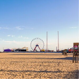 a ferris wheel on the beach with people walking around