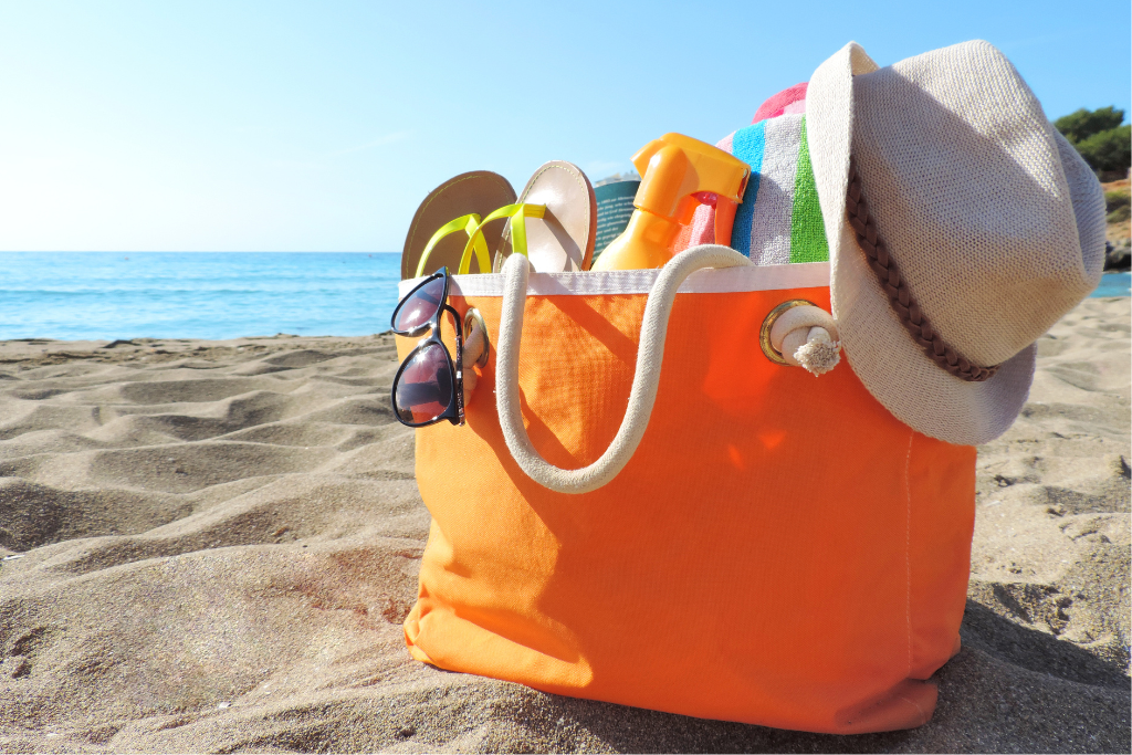 Orange bag with beach supplies sitting on sand