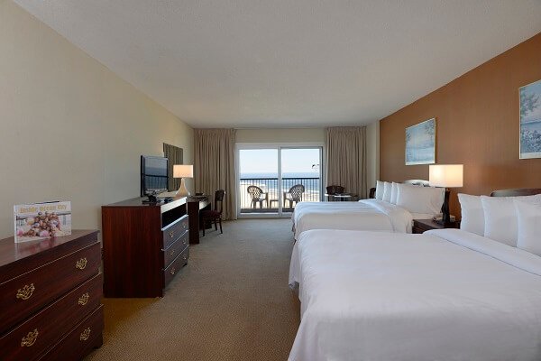 hotel room with two queen beds dressers and oceanfront balcony