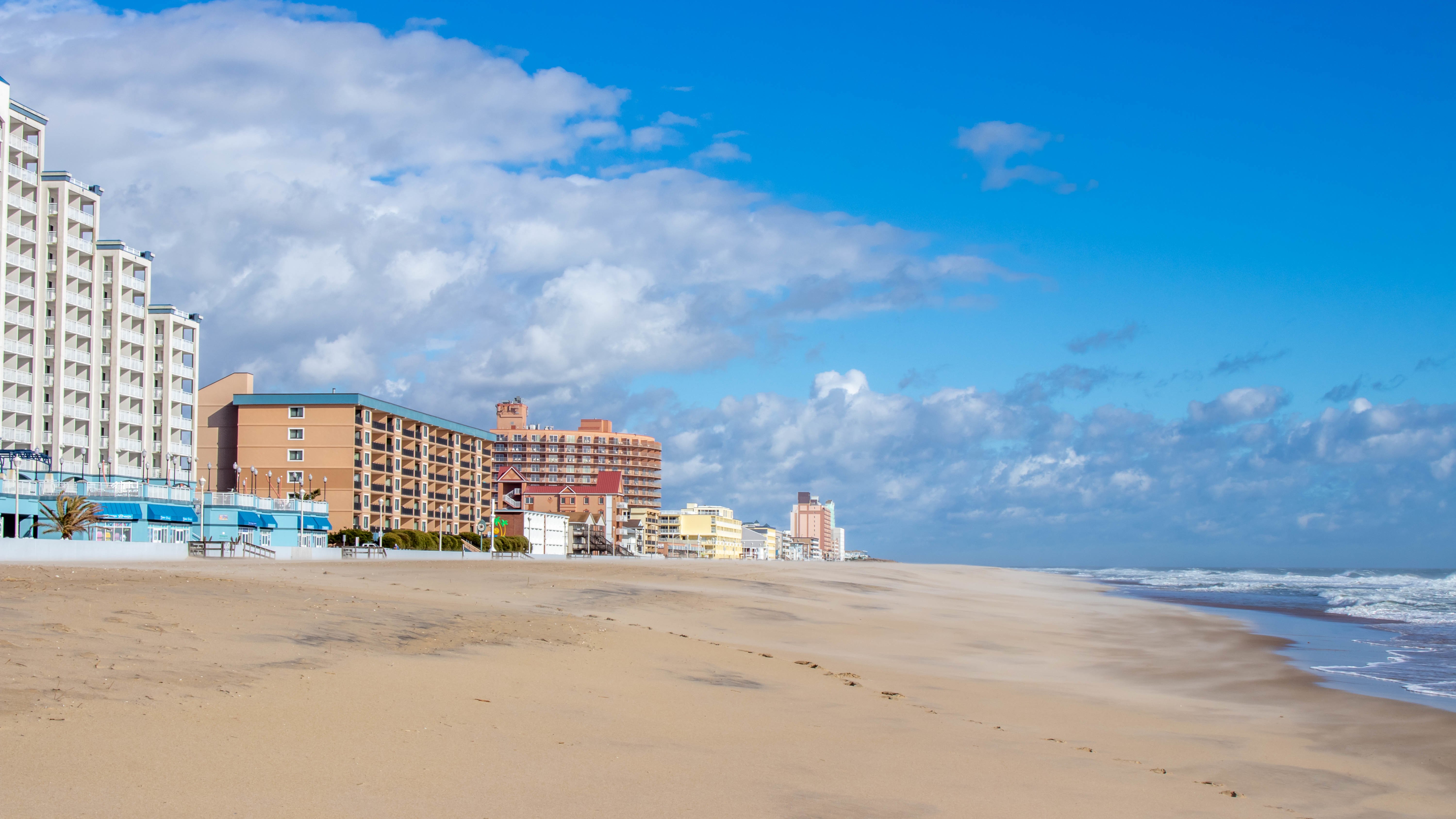 A beach scene with several buildings, including a large hotel, in the background.