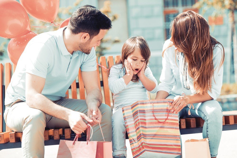 Family showing their young daughter items in a gift bag