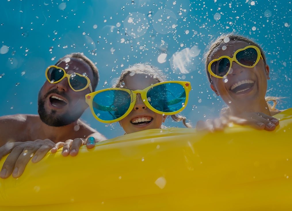 image of mom and dad with daughter in the middle wearing yellow sunglasses