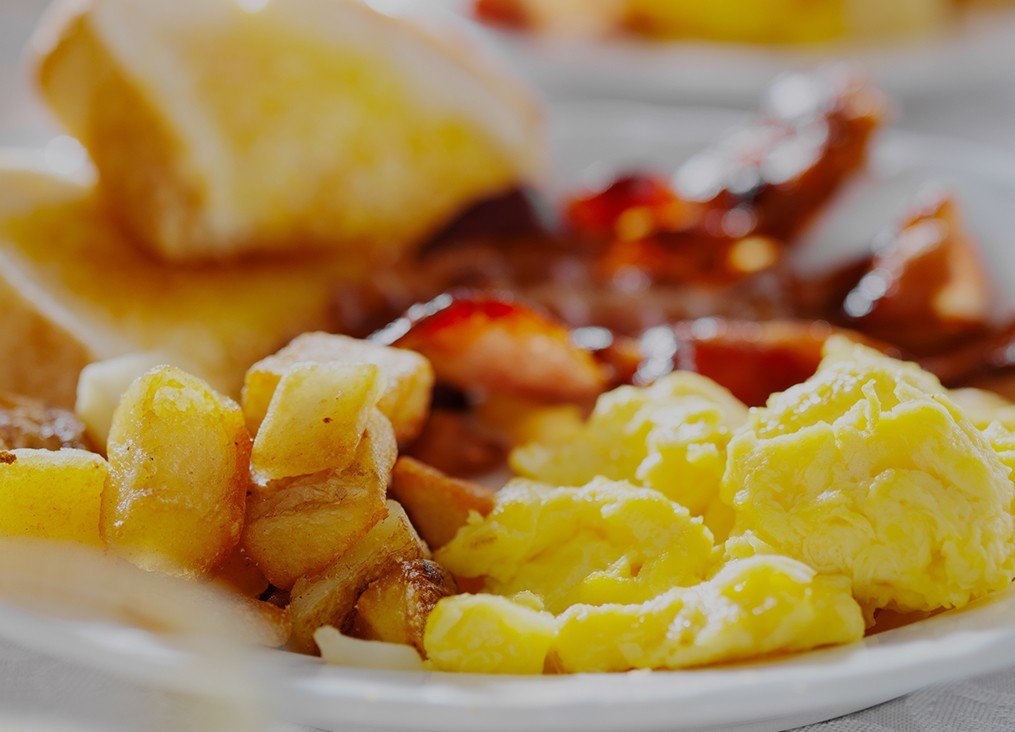 close up of breakfast plate with eggs, potatoes and bacon