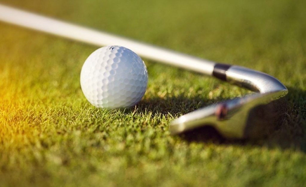 close up of golf club and ball on green