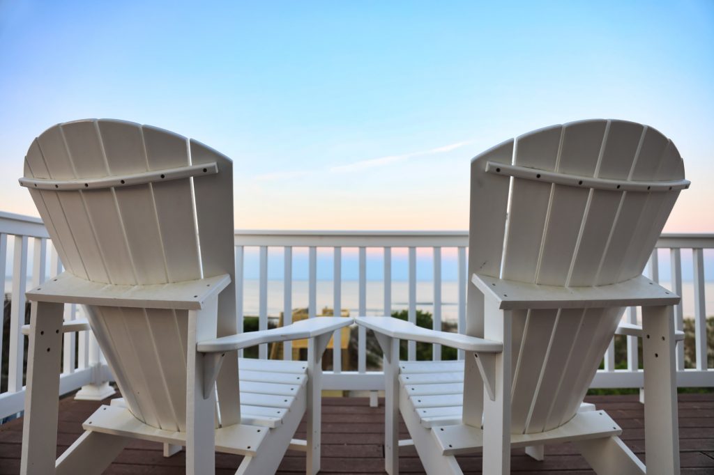 Adirondack chairs on a balcony facing the ocean
