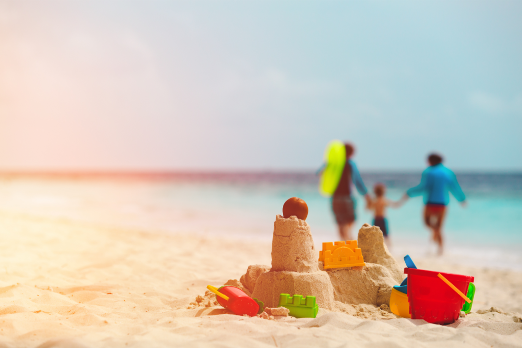 Sand castle and beach toys with family in the background