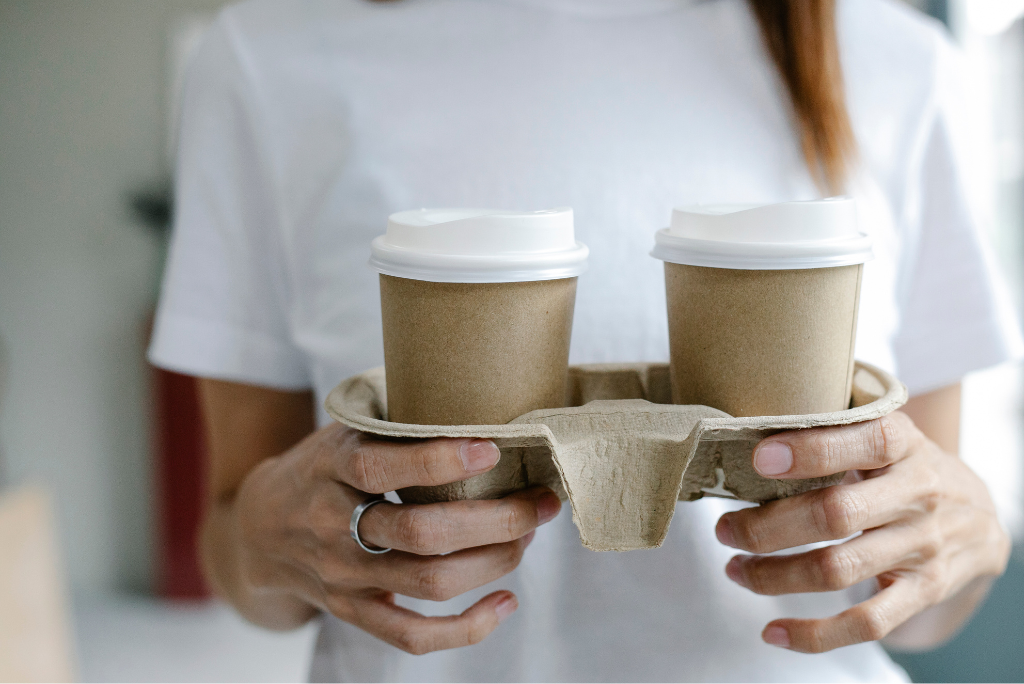 a woman holding two to-go coffees