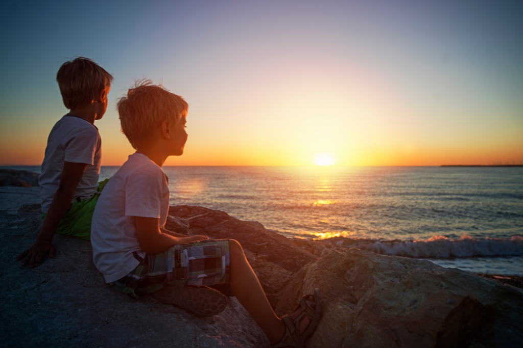 two boys on the beach at sunset