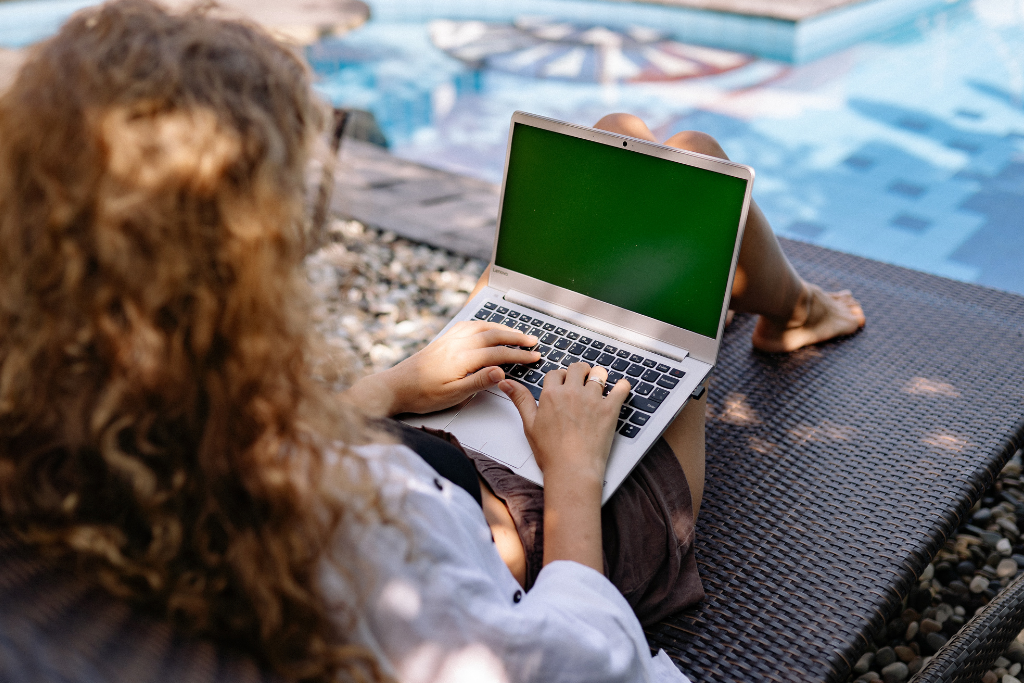Woman working on laptop by a pool