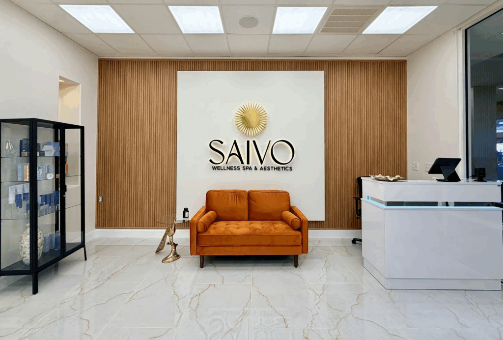 A modern spa lobby with a reception desk, a waiting area with a sofa, and a display case.