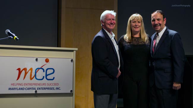 2017 entrepreneur of the year finalist and officials posing on stage next to podium