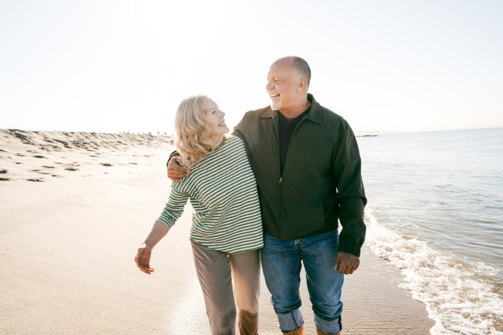 Man and women arm-in-arm walking on beach