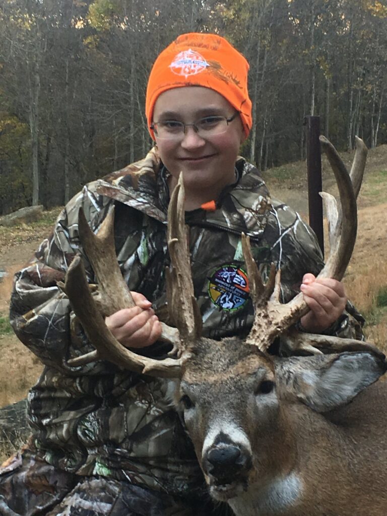 a young boy wearing an orange headband holding a deer's antlers