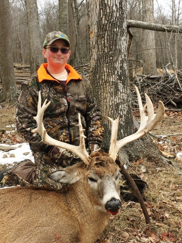 a man is posing with a deer in the woods