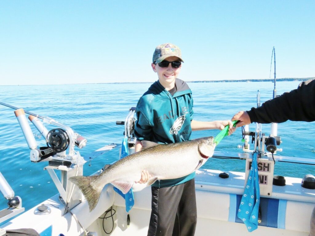 a man holding a fish while standing on a boat