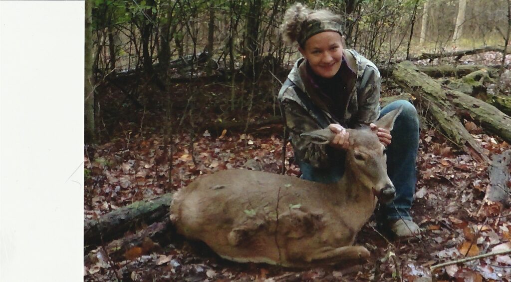 a woman kneeling down next to a deer