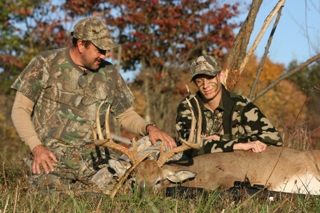 a couple of men kneeling next to a deer