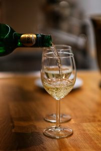 pouring white wine into 2 glasses