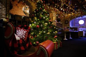 Big red sleigh beside a lit up Christmas tree inside Nick's in OCMD