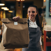 woman handing a bag of take out food