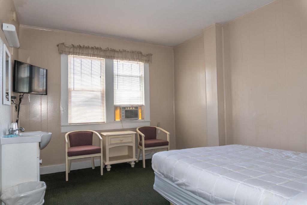 standard queen room with bed, table and chairs, sink, and tv