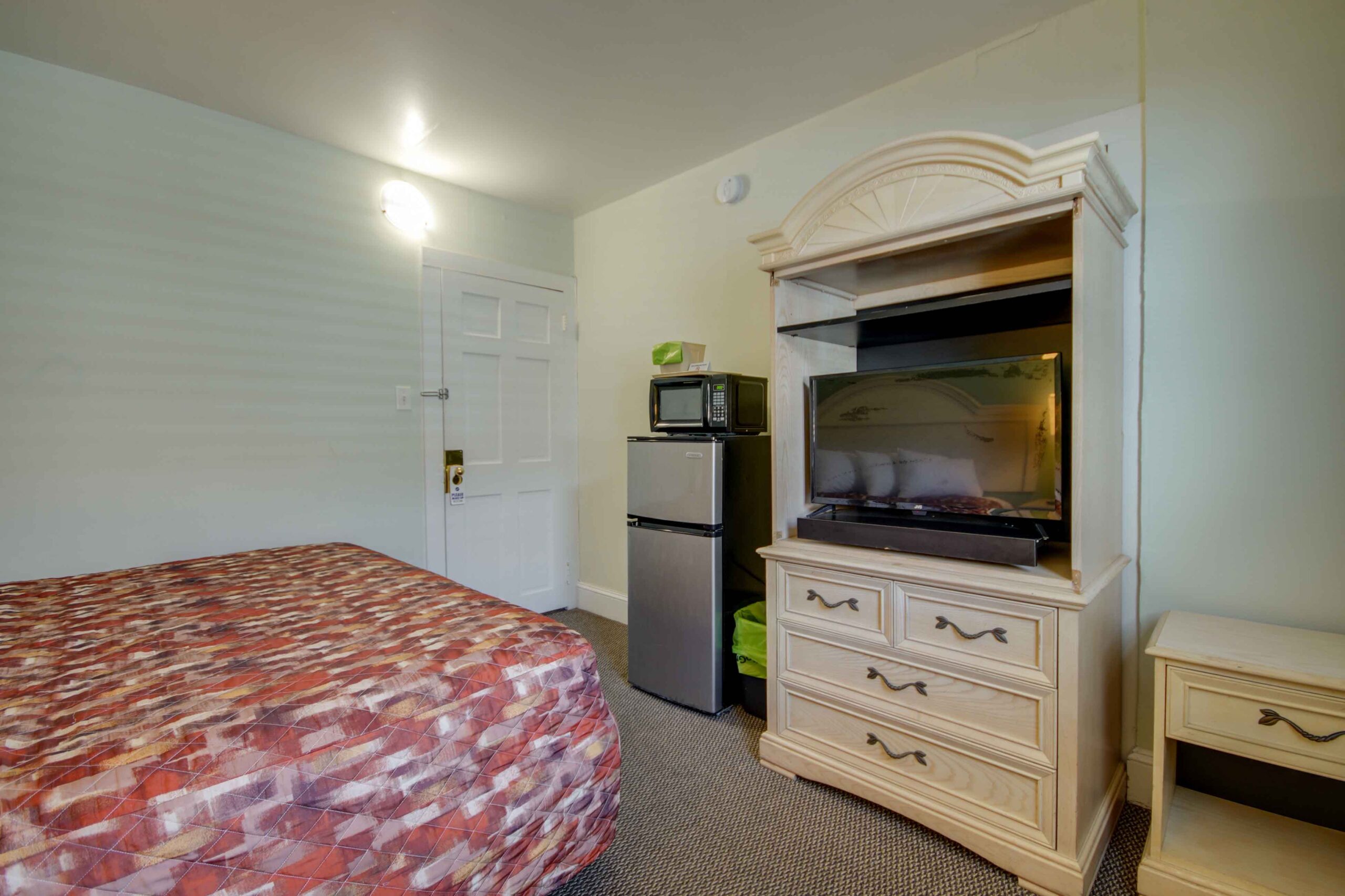 hotel room with king bed tv and fridge