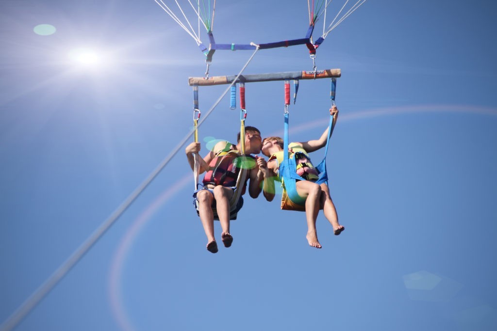 Happy couple kissing while parasailing