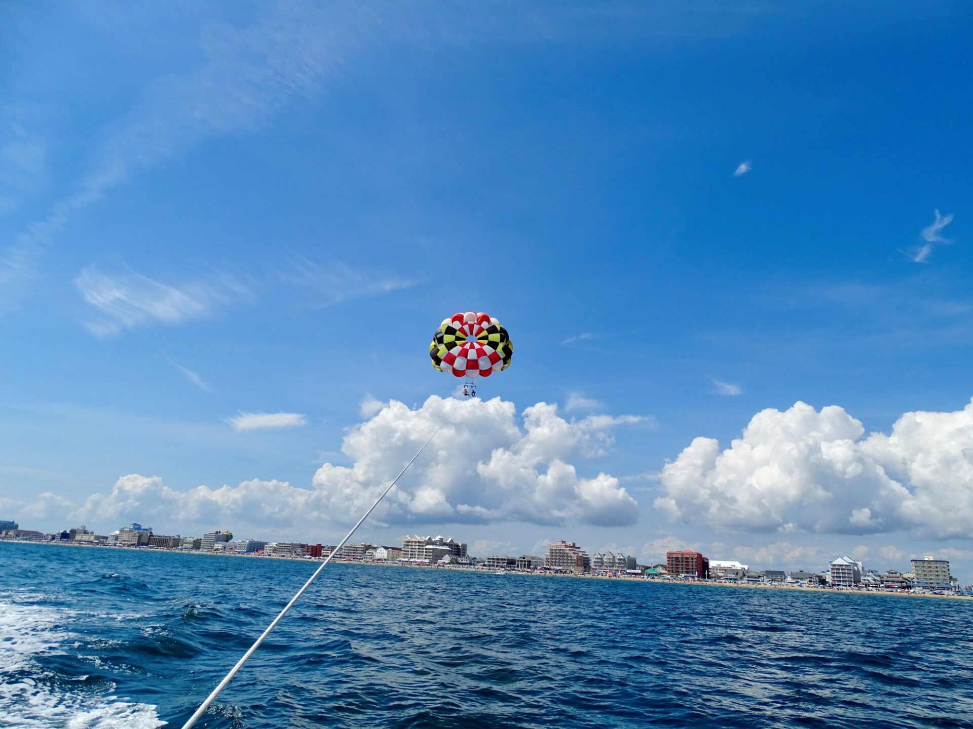couple parasailing in Ocean City, MD with a MD flag parachute and ocmd skyline