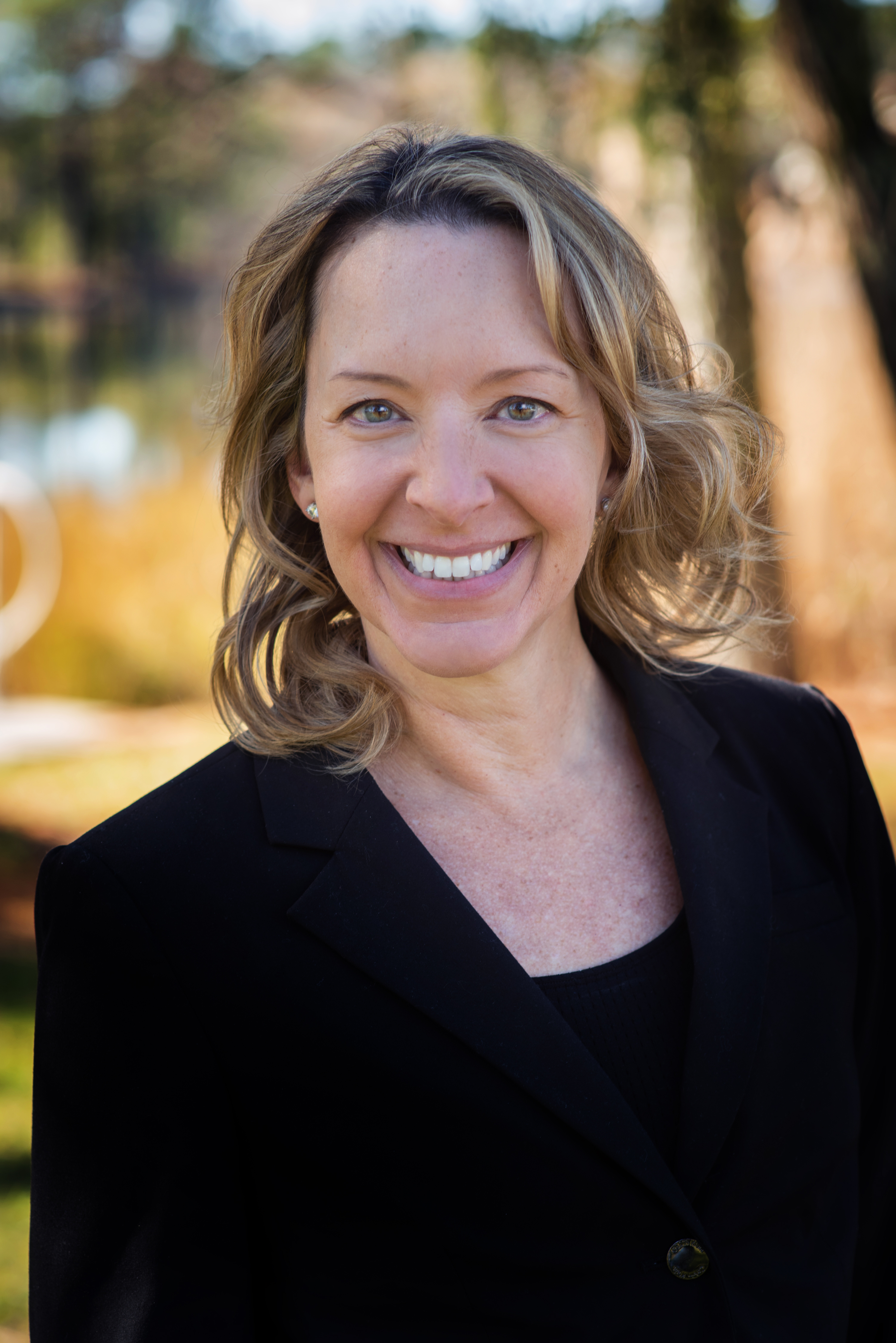 a woman in a black suit smiling for the camera