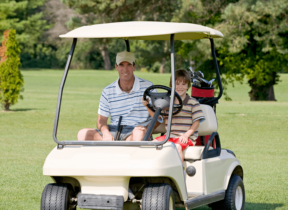 Father and Son in a golf cart smiling