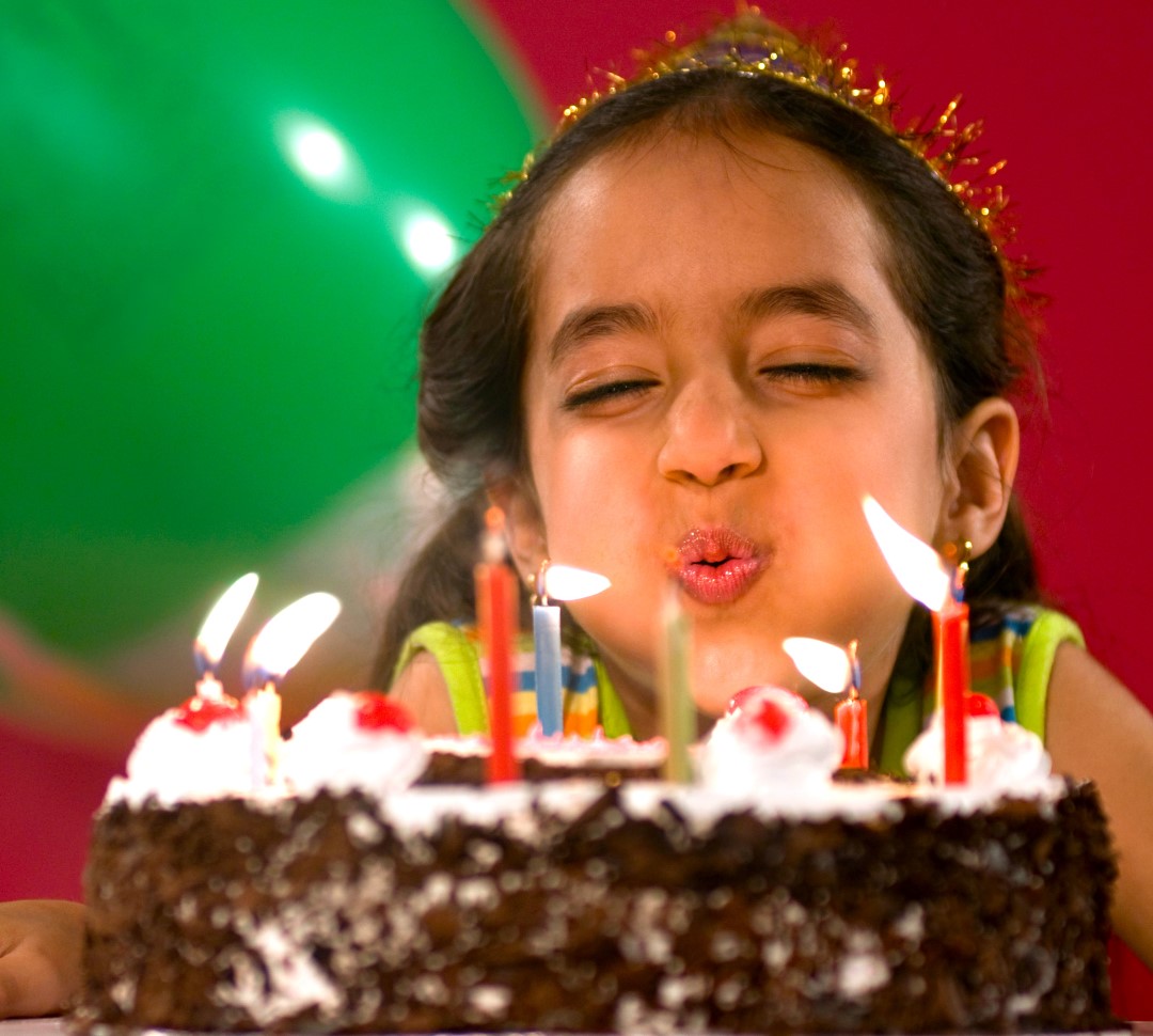 Young girl blowing out candles on a birthday cake