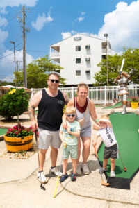 a man, woman and child are playing miniature golf