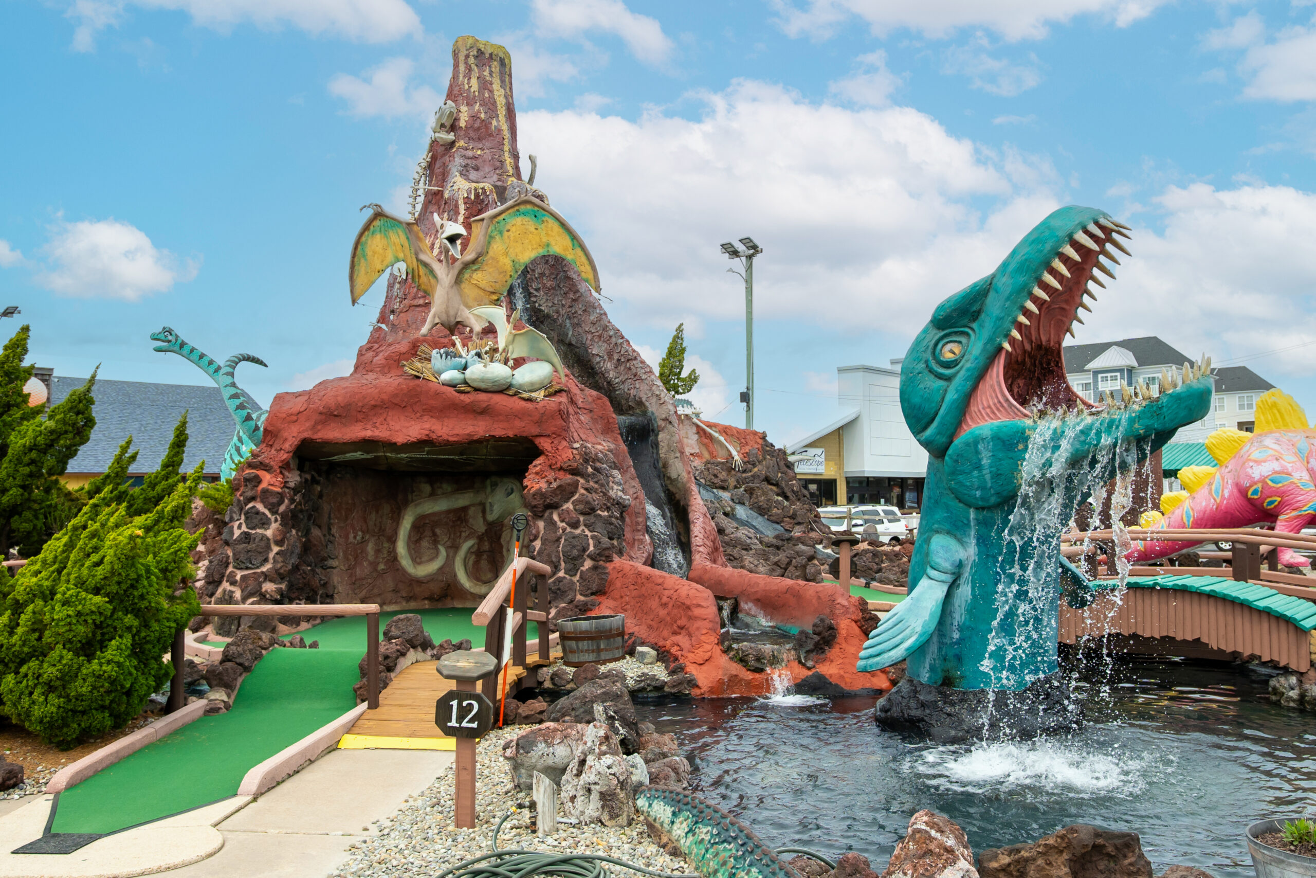 a water park with a fountain and a fake dinosaur