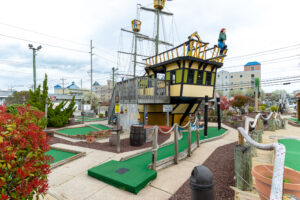 a miniature golf course with a pirate ship in the background
