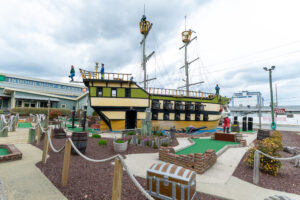 a miniature golf course with a boat in the background