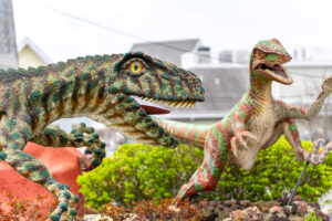 a couple of statues of dinosaurs in a garden