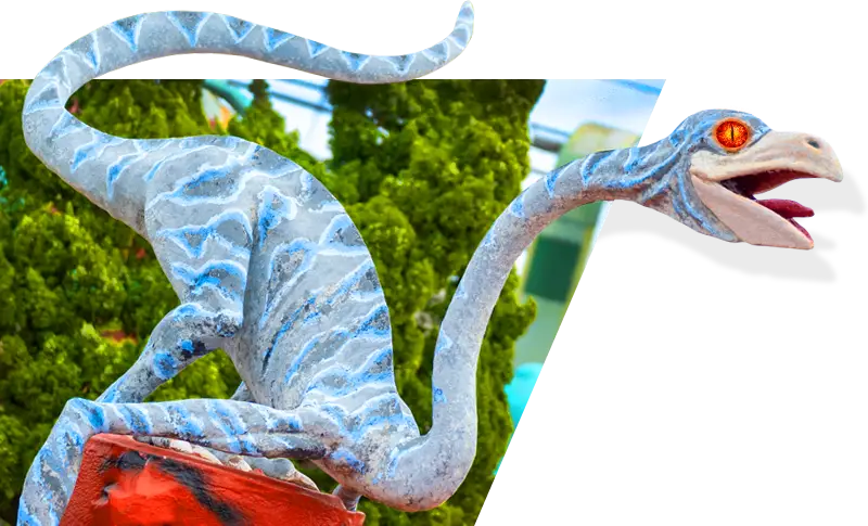 a statue of a lizard holding a red bag