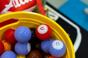 a bucket filled with different colored balls next to a can of soda